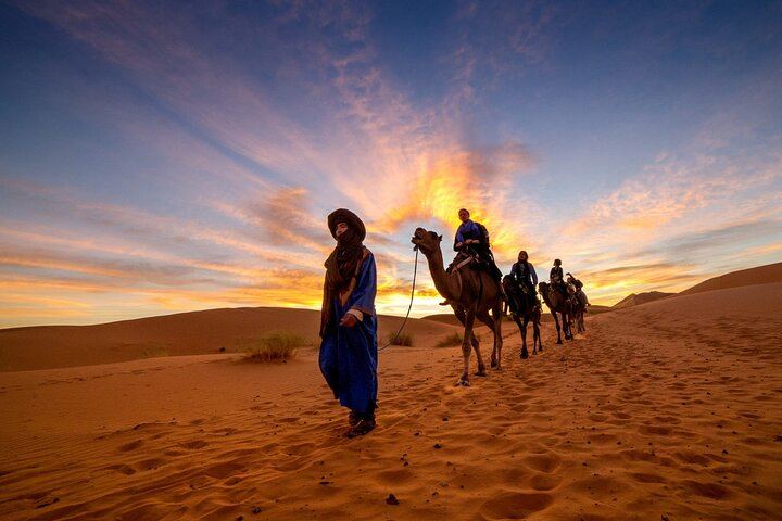 Caravane de chameaux traversant les dunes du désert de Merzouga au coucher du soleil